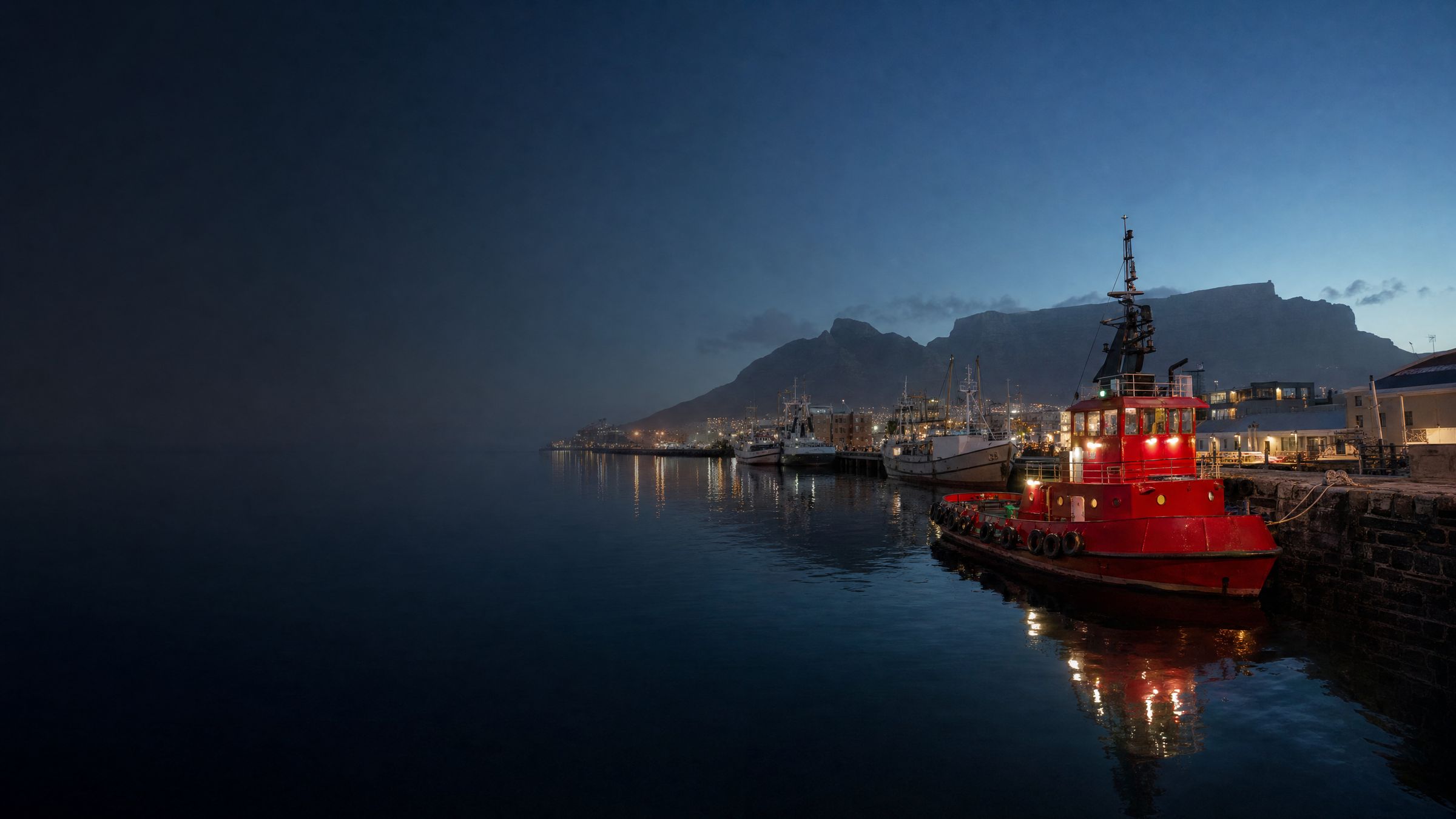A red tugboat in the V&A Waterfront harbour below Table Mountain