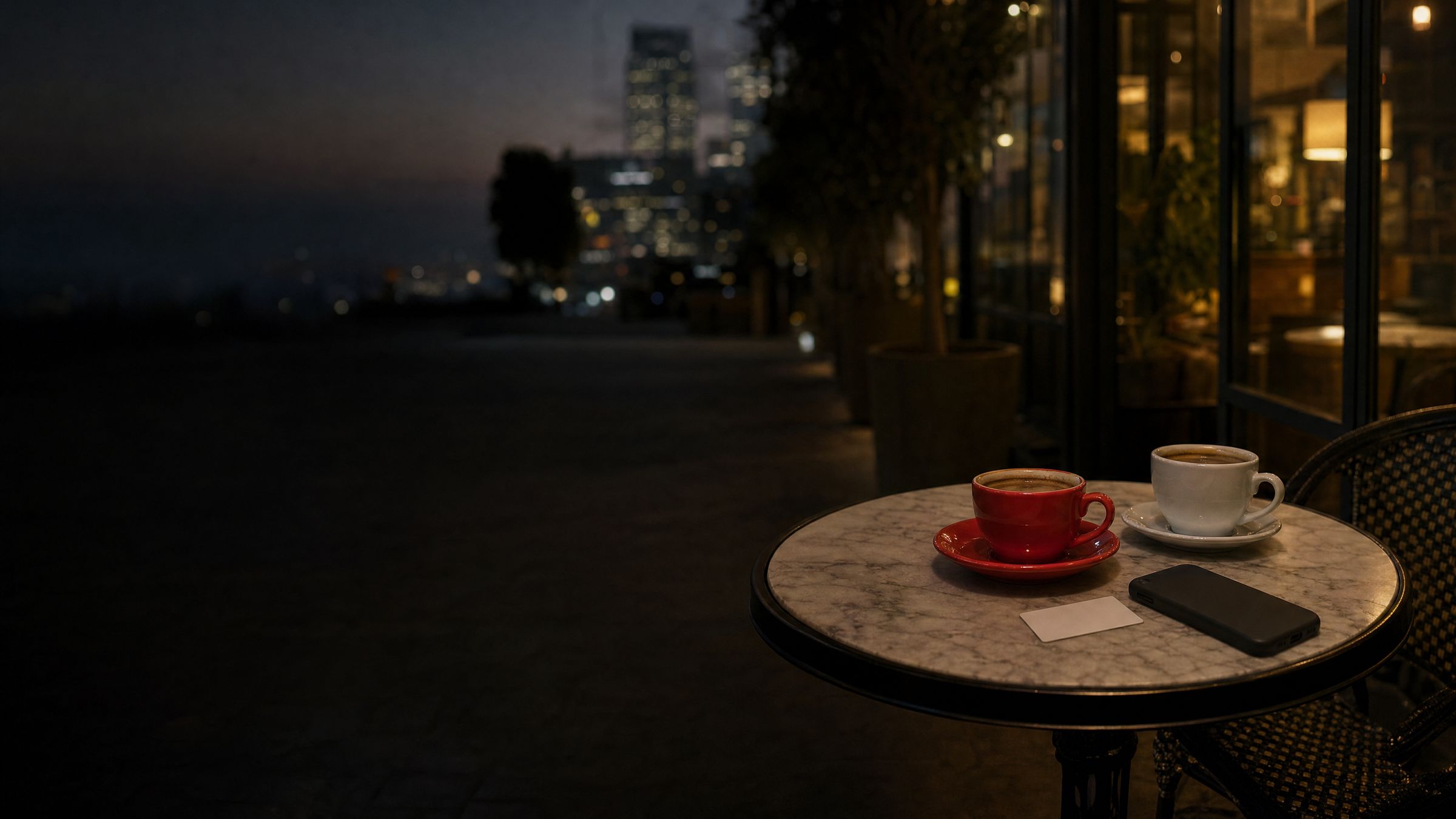 Two coffee cups, a phone and a business card on a Sandton cafe table